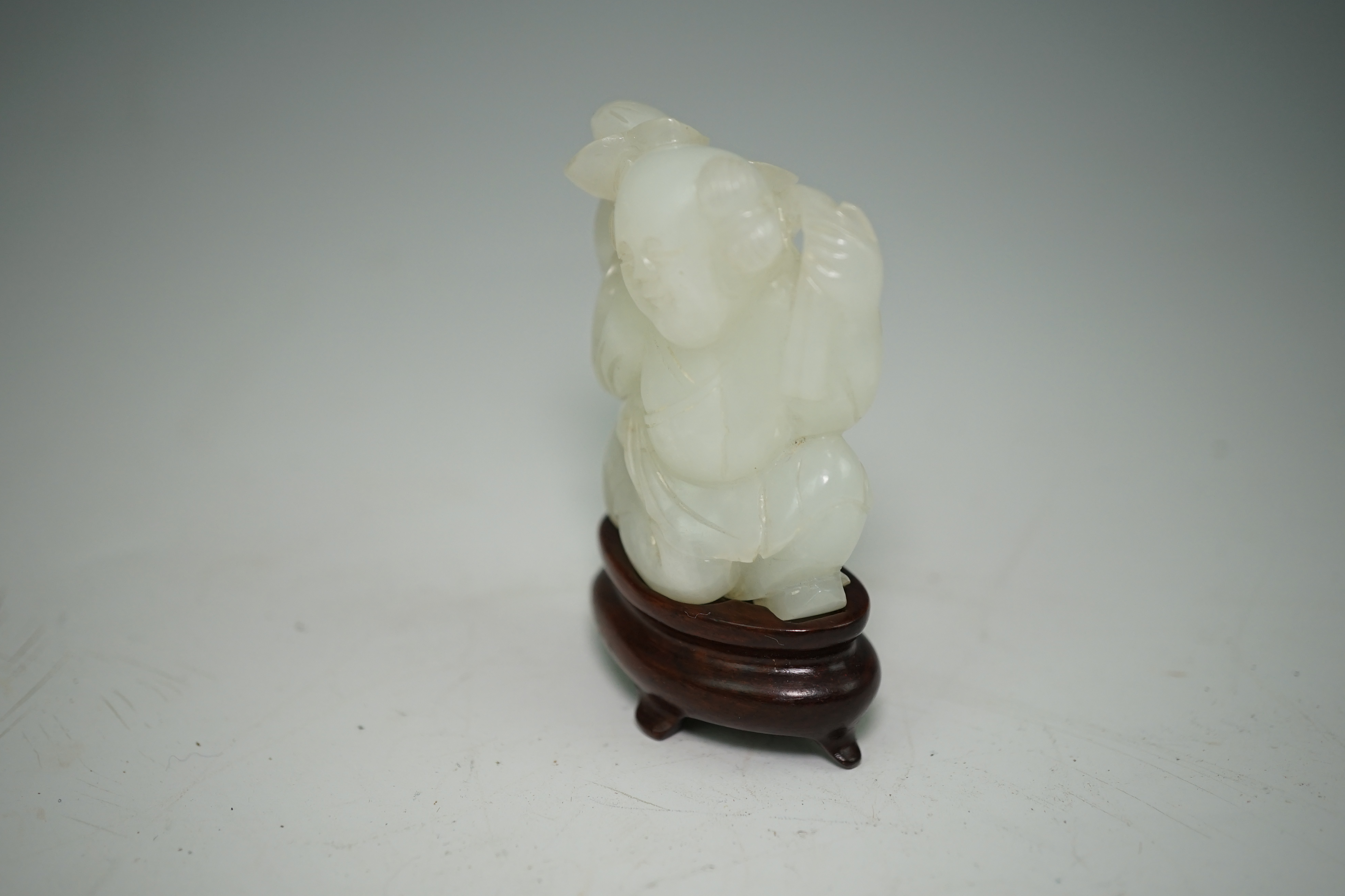 A Chinese white jade figure of a kneeling boy holding lingzhi fungus, 19th century